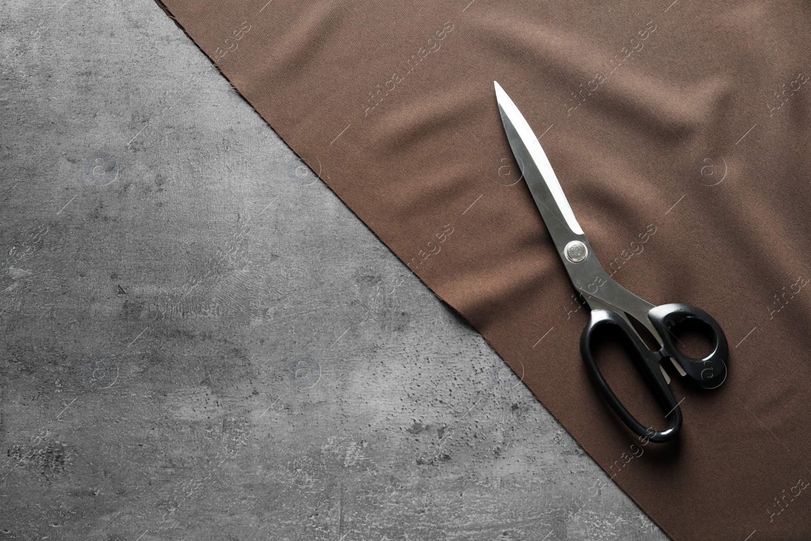 Photo of Scissors and fabric on grey background, top view. Tailoring equipment