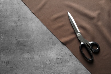 Photo of Scissors and fabric on grey background, top view. Tailoring equipment