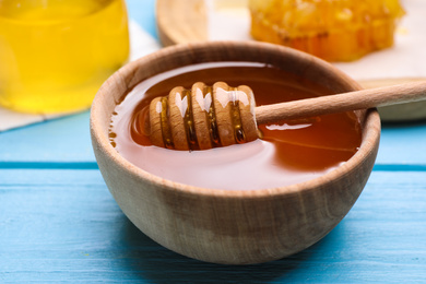 Photo of Tasty aromatic honey on light blue wooden table, closeup