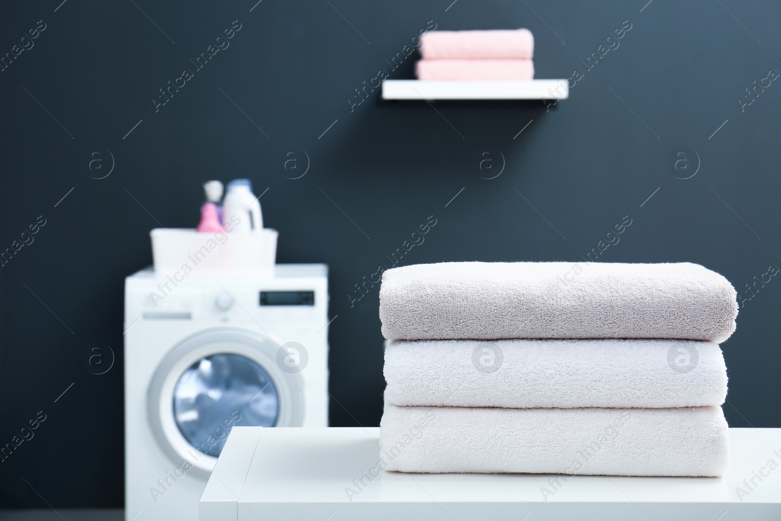 Photo of Stack of clean towels on table in laundry room. Space for text