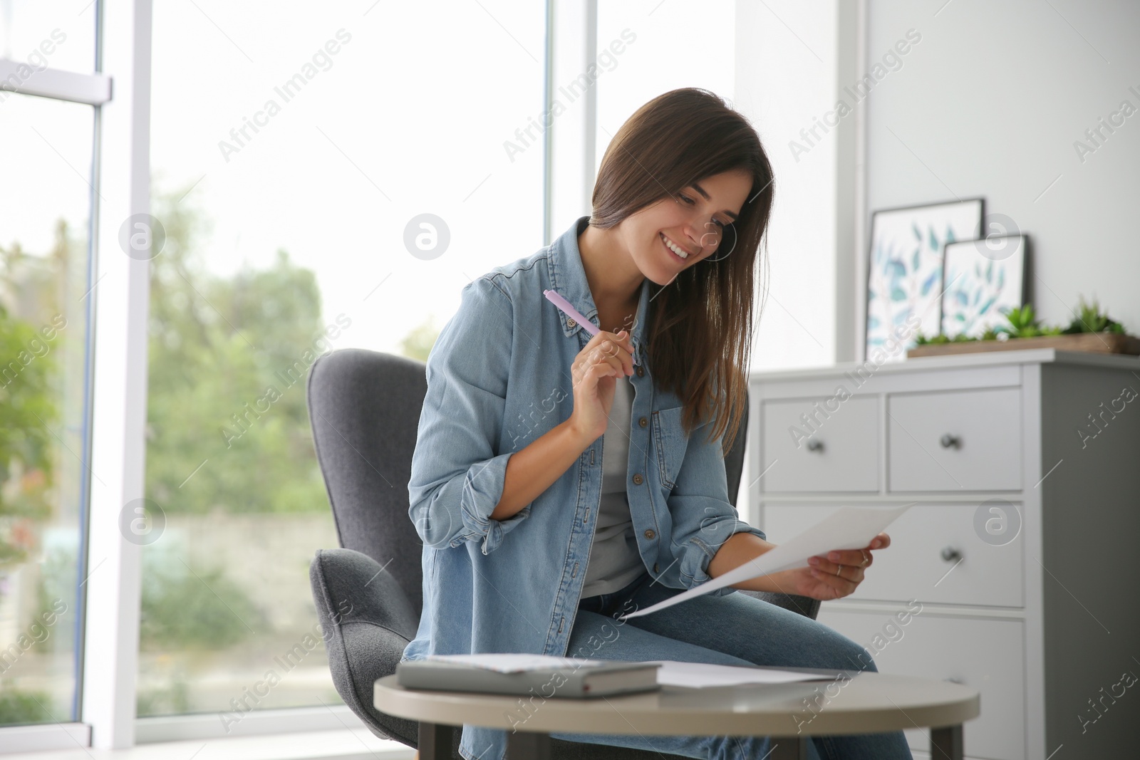 Photo of Woman writing paper letter at table indoors