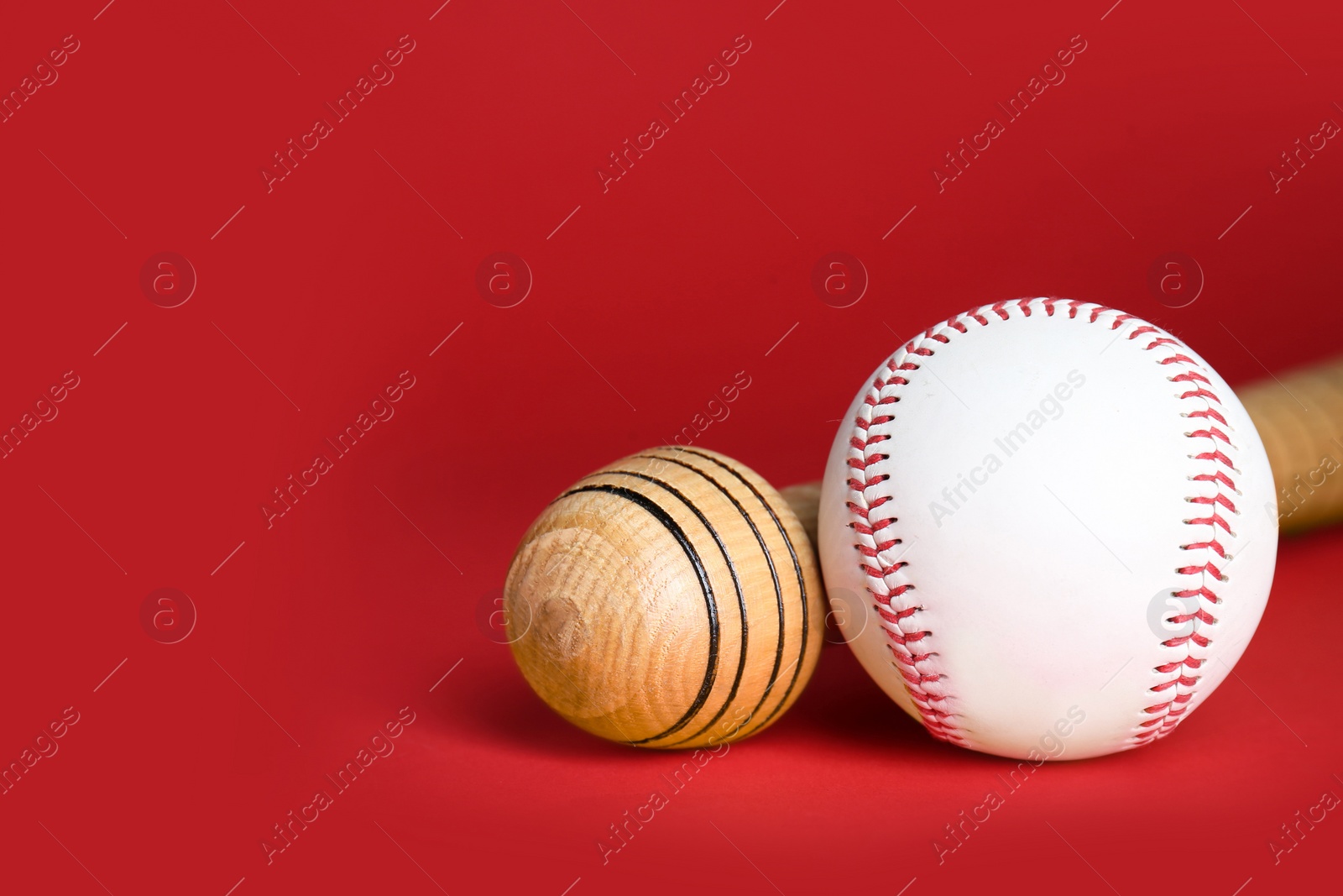 Photo of Wooden baseball bat and ball on red background, closeup. Space for text