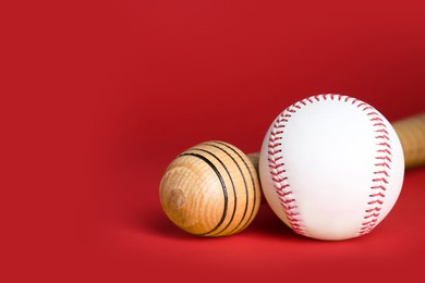 Photo of Wooden baseball bat and ball on red background, closeup. Space for text