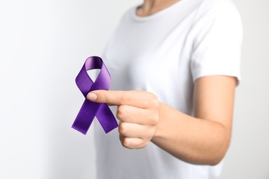 Woman holding purple ribbon on white background, closeup. Domestic violence awareness