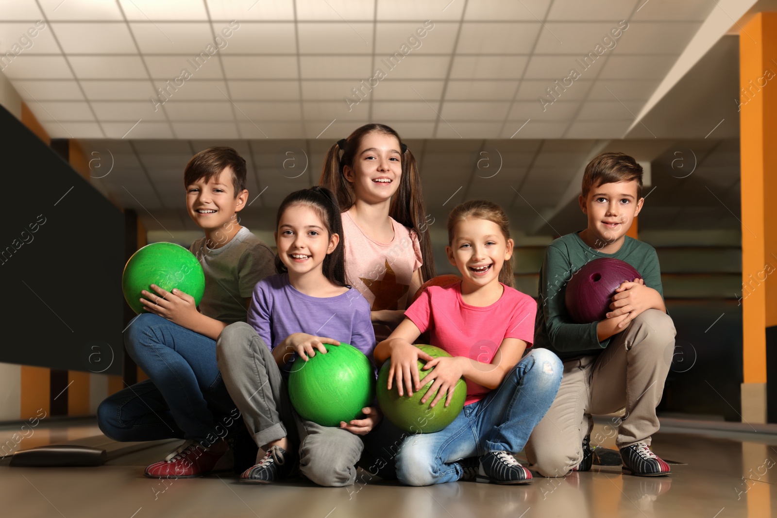 Photo of Happy children with balls in bowling club