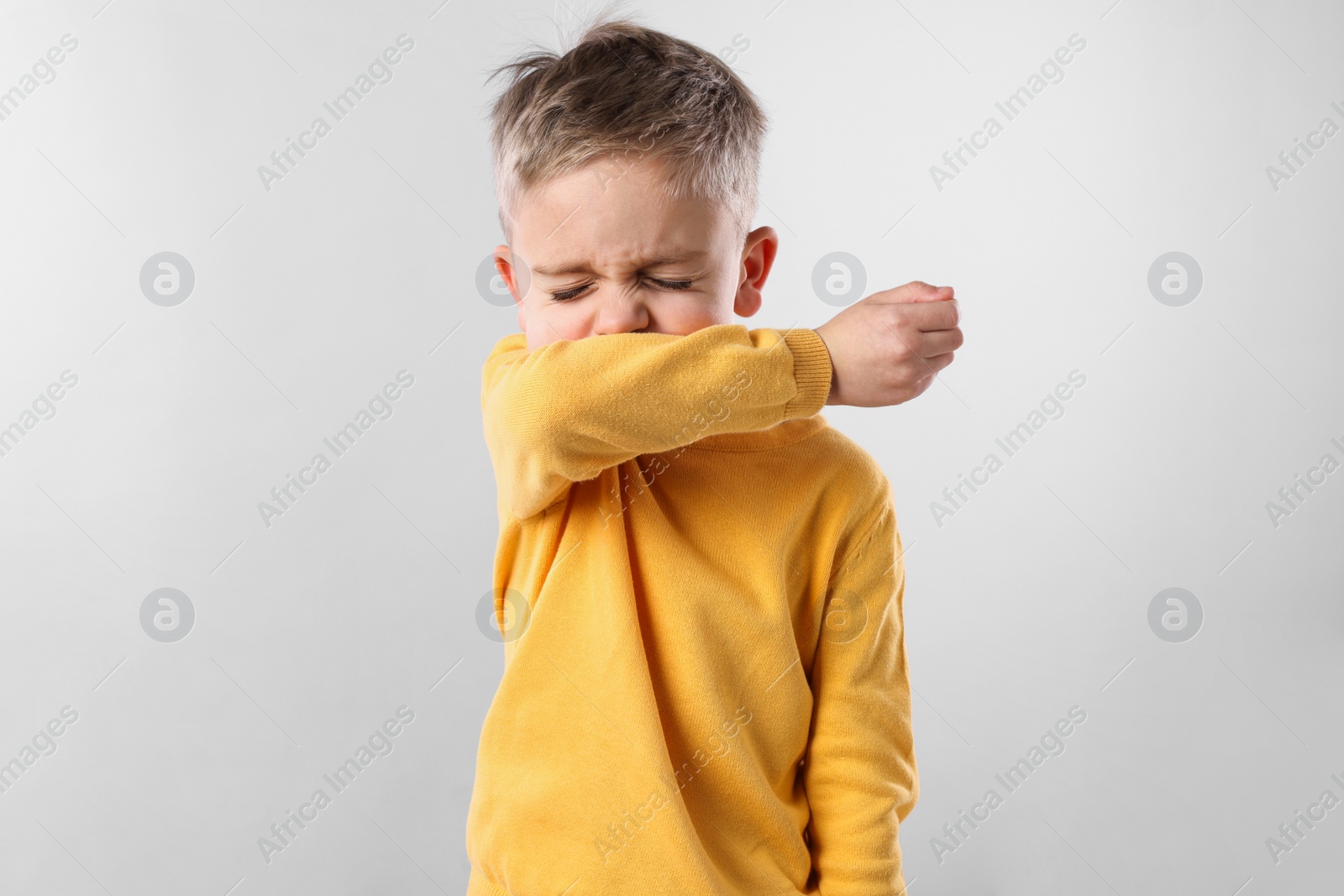 Photo of Sick boy coughing on gray background. Cold symptoms