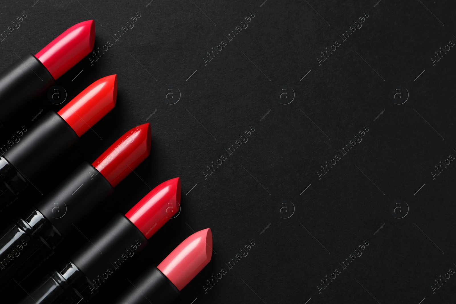 Photo of Beautiful lipsticks on black background, flat lay. Space for text