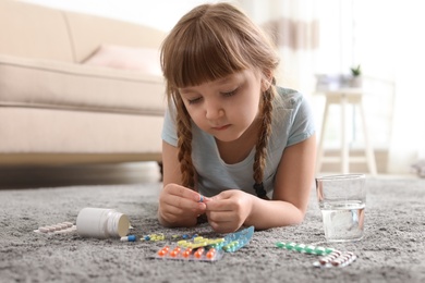 Little child with many different pills on floor at home. Danger of medicament intoxication