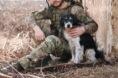 Photo of Ukrainian soldier with stray dog sitting outdoors, closeup