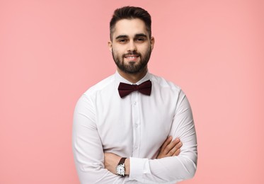 Portrait of smiling man in shirt and bow tie on pink background