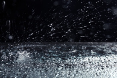 Photo of Rain drops falling down against dark background