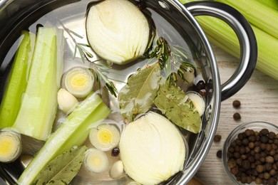 Photo of Pot and different ingredients for cooking tasty bouillon on white wooden table, flat lay