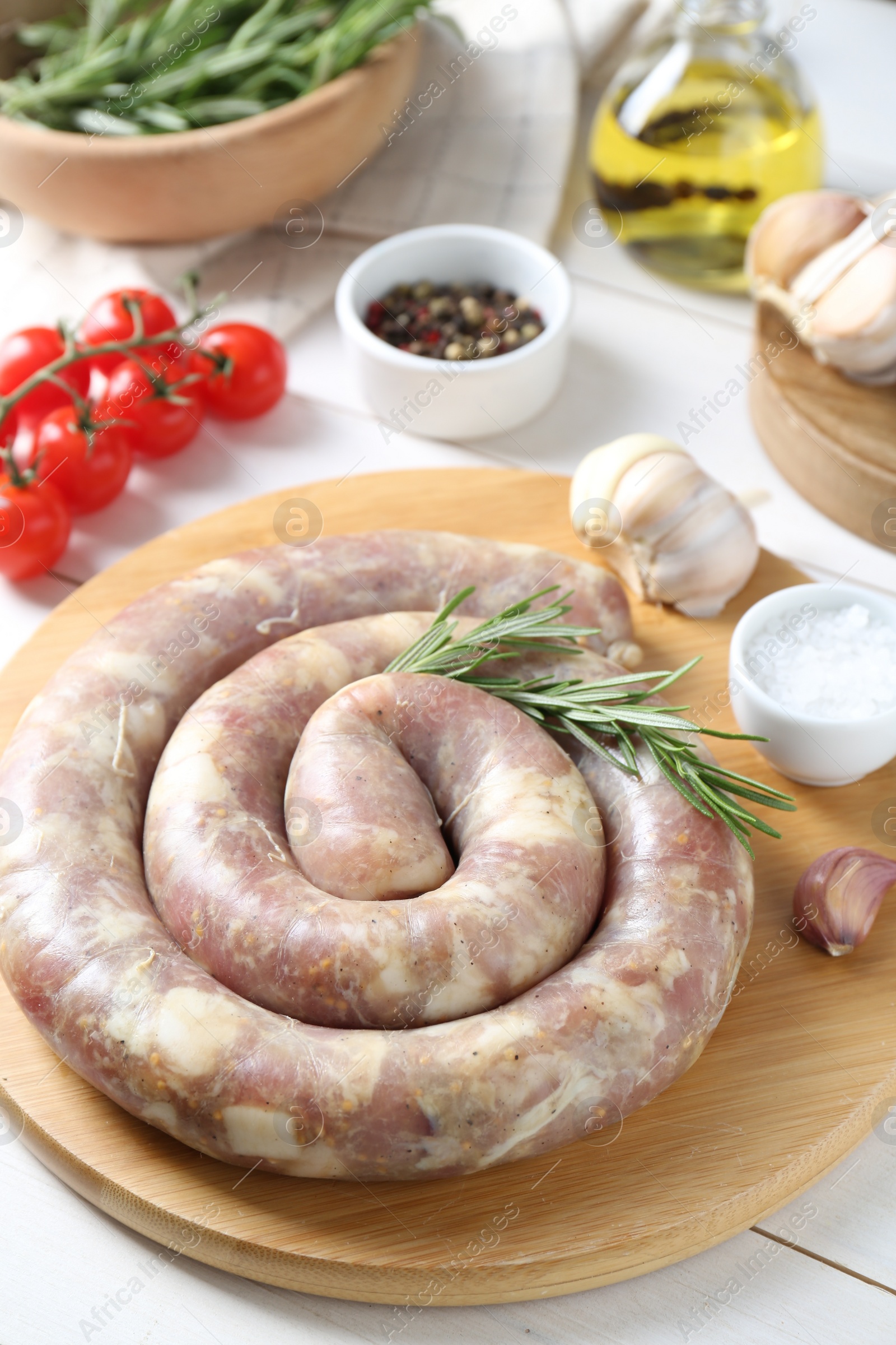 Photo of Raw homemade sausage, spices and other products on white wooden table, closeup