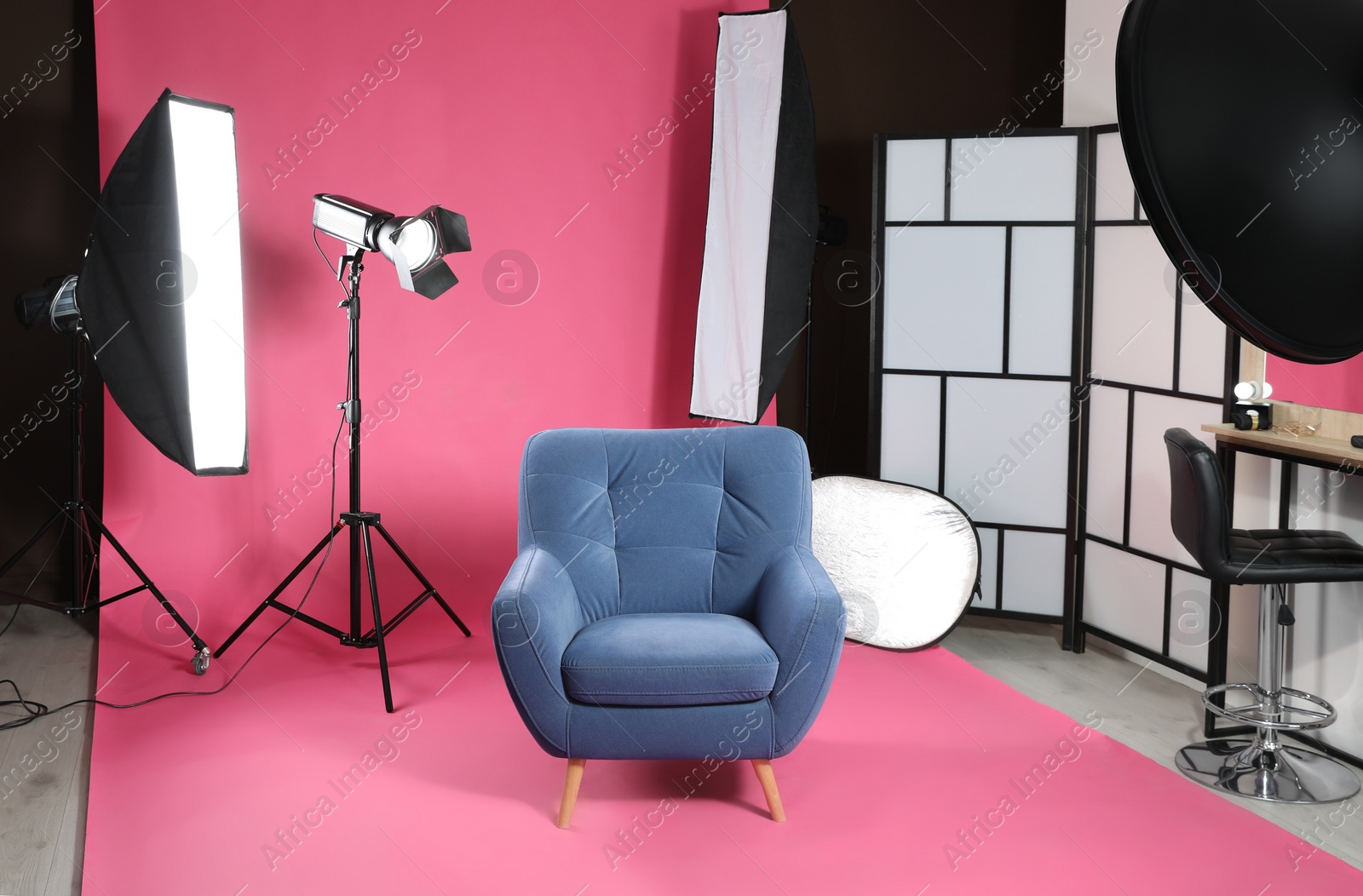 Photo of Stylish blue armchair in photo studio with professional equipment