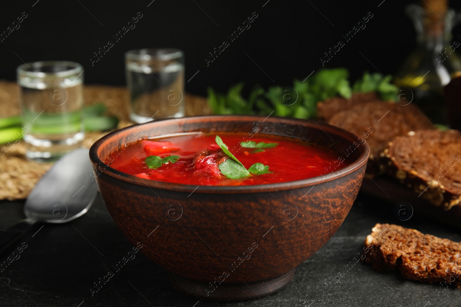 Photo of Stylish brown clay bowl with Ukrainian borsch on black table