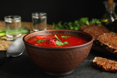 Photo of Stylish brown clay bowl with Ukrainian borsch on black table