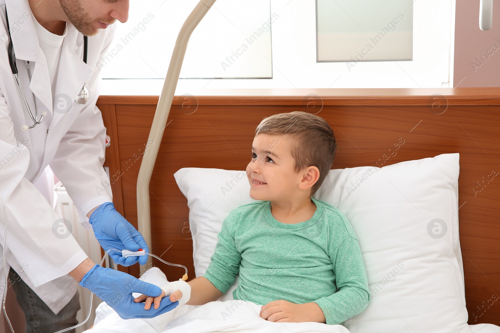Photo of Doctor adjusting intravenous drip for little child in hospital