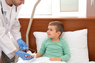 Doctor adjusting intravenous drip for little child in hospital