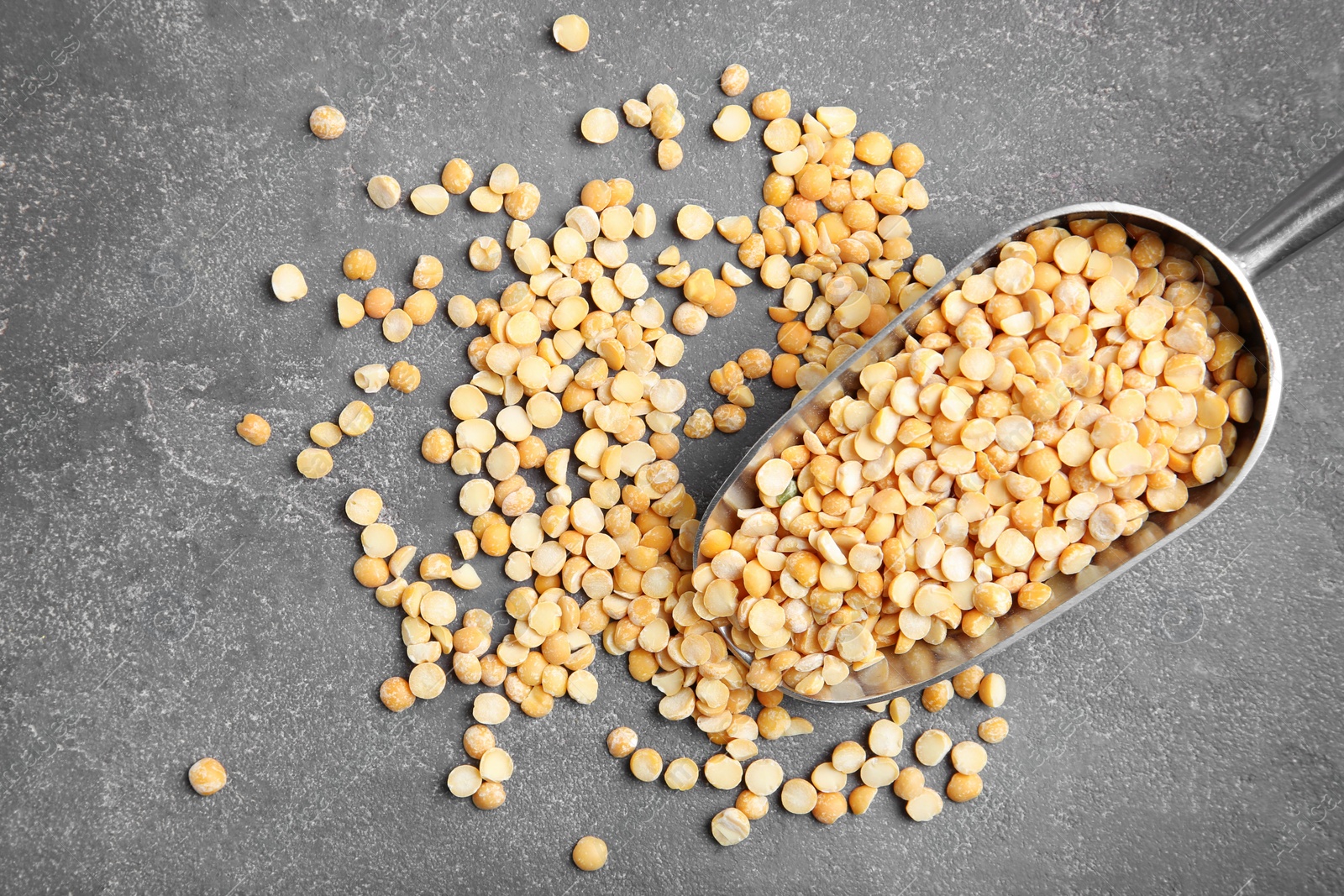 Photo of Metal scoop with dried peas on grey background, top view