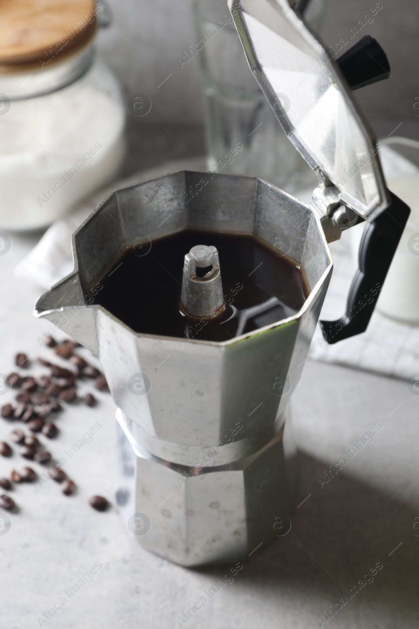 Photo of Brewed coffee in moka pot and beans on light grey table