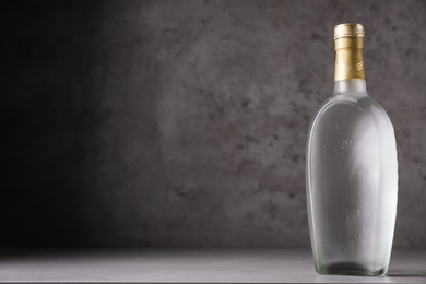 Photo of Bottle of vodka on table against grey background. Space for text