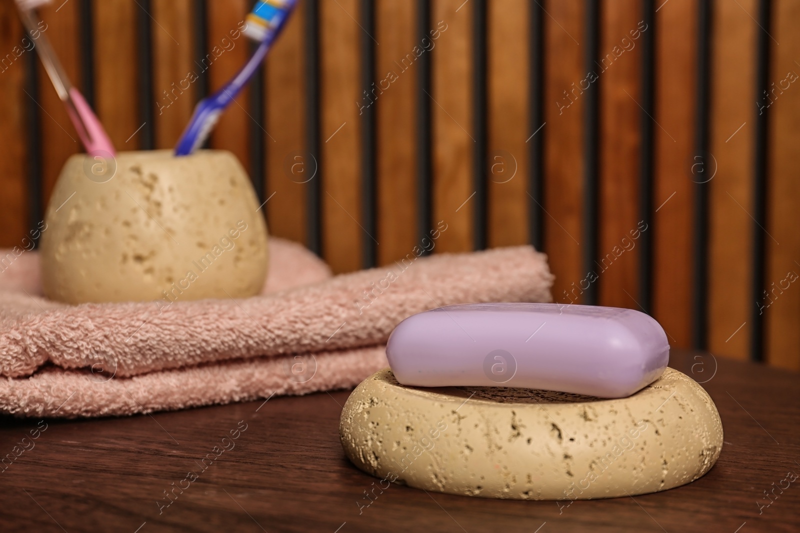 Photo of Dish with soap bar on table against blurred background. Space for text