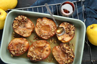 Tasty baked quinces with nuts and honey in dish on table, flat lay