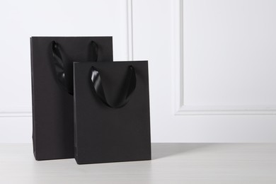 Photo of Black paper bags on white wooden table, space for text