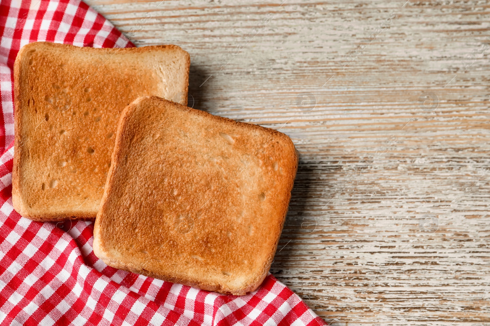 Photo of Slices of delicious toasted bread on wooden table, top view. Space for text