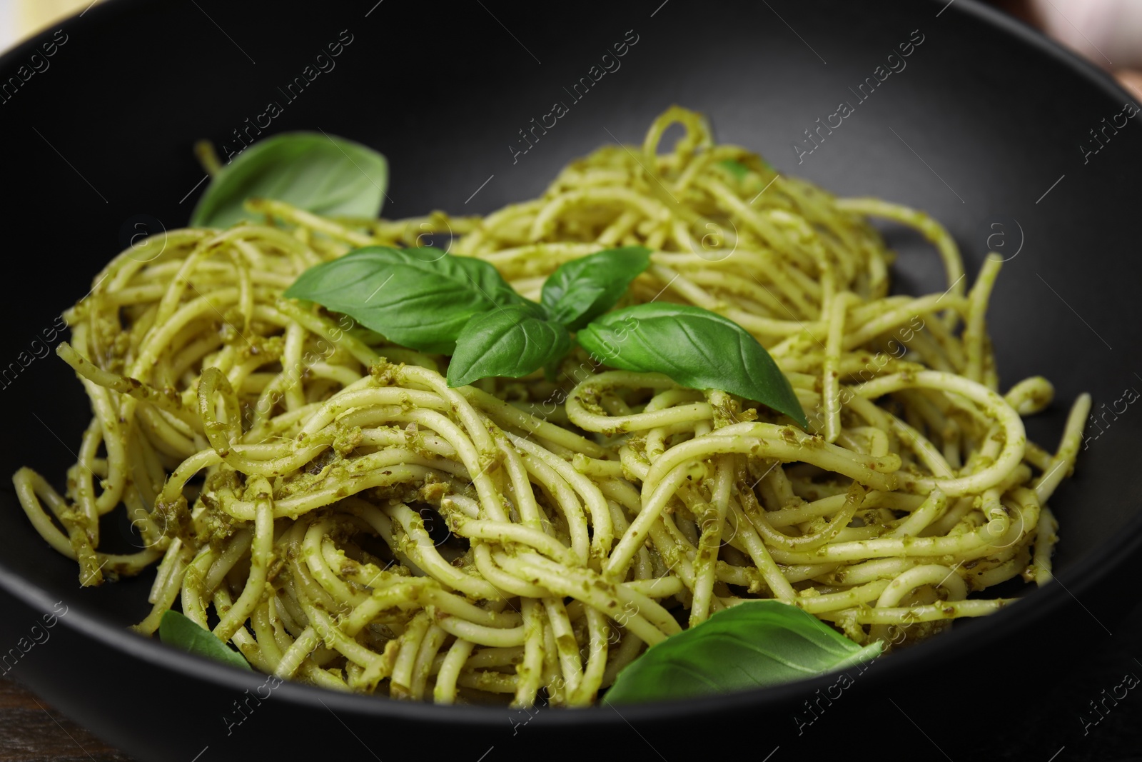 Photo of Delicious pasta with pesto sauce and basil in bowl, closeup
