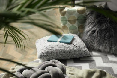 Notebook, soft pillows and plaids on window sill in room. Cozy place to relax