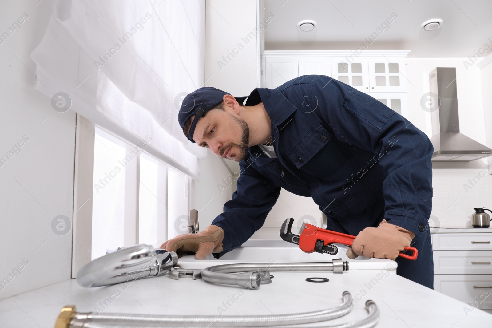 Photo of Professional plumber fixing water tap in kitchen