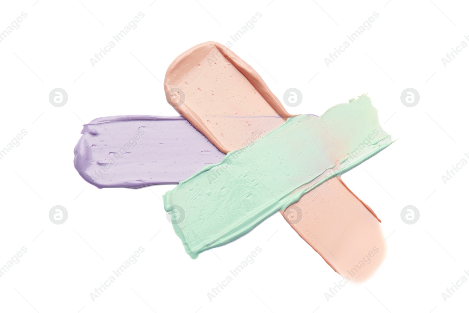 Photo of Strokes of pink, green and purple color correcting concealers isolated on white, top view