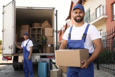 Workers unloading boxes from van outdoors. Moving service