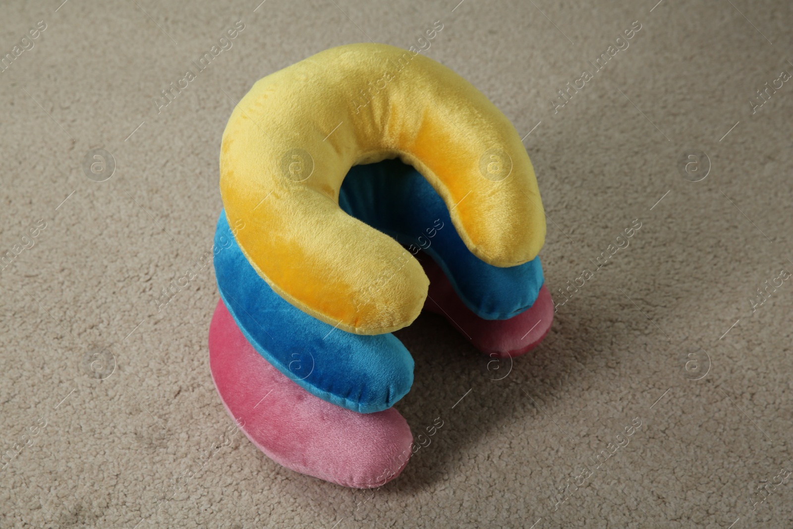 Photo of Many colorful travel pillows on beige rug