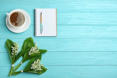 Photo of Flat lay composition with notebook, lily of the valley bouquets and coffee on wooden background. Space for text