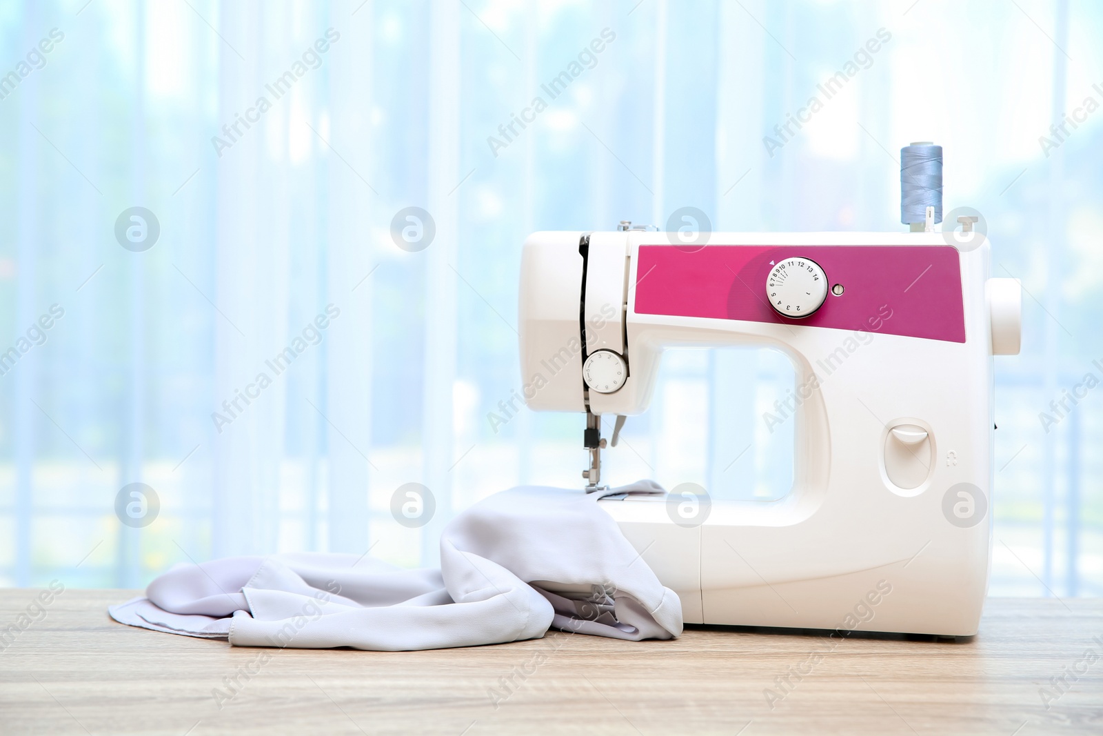 Photo of Sewing machine on table near window indoors