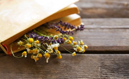 Photo of Closed book with beautiful dried flowers on wooden table, closeup. Space for text