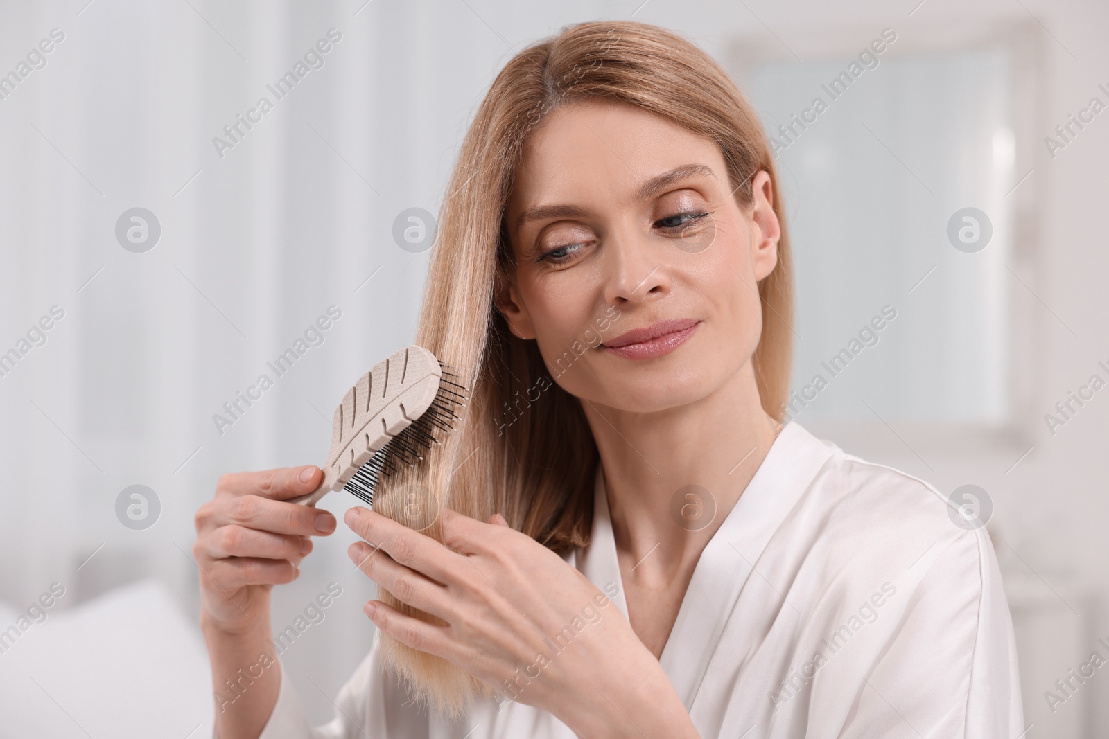 Photo of Beautiful woman brushing her hair in room