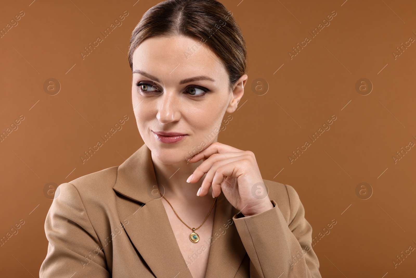 Photo of Beautiful woman with elegant necklace on brown background