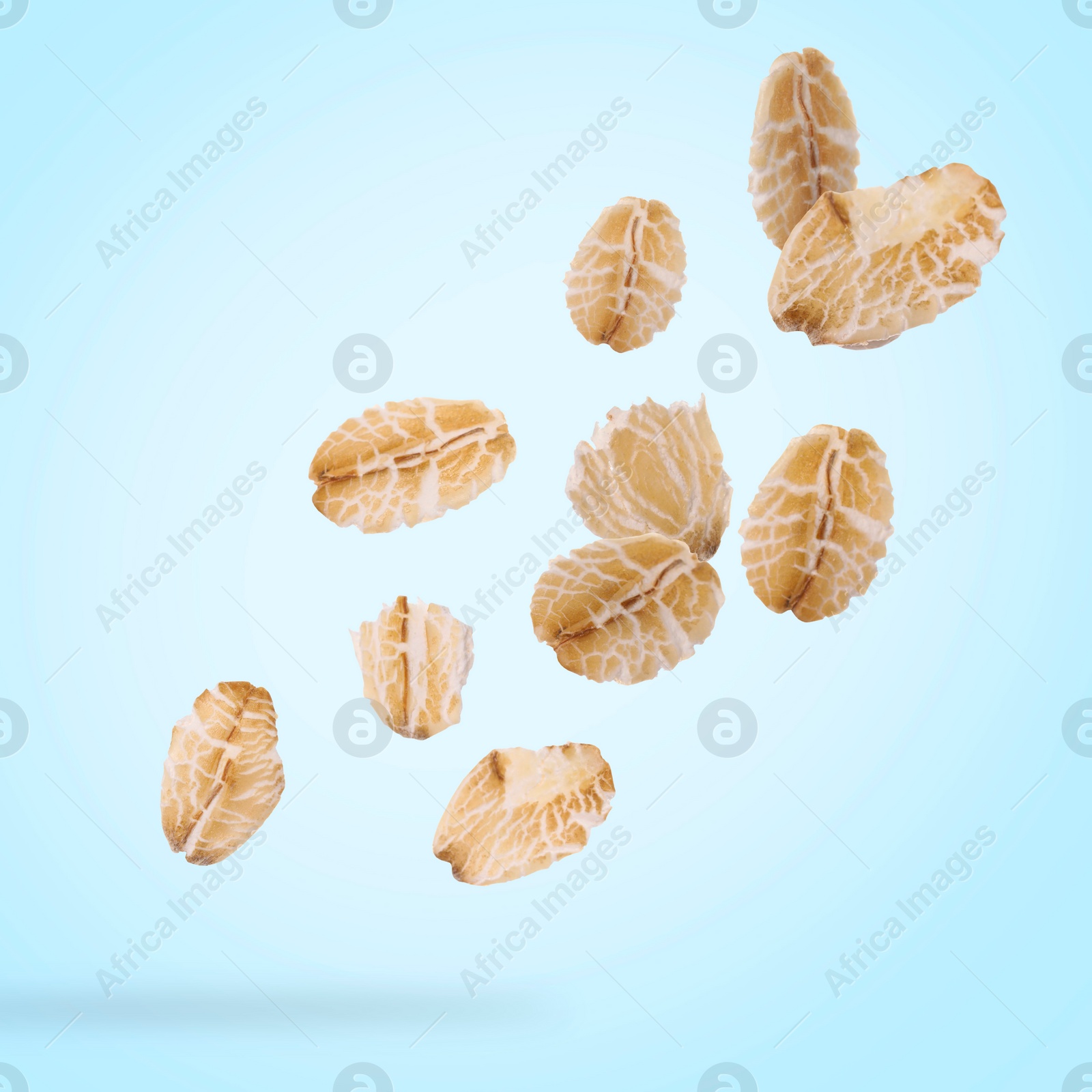 Image of Rolled oat flakes falling on light blue background