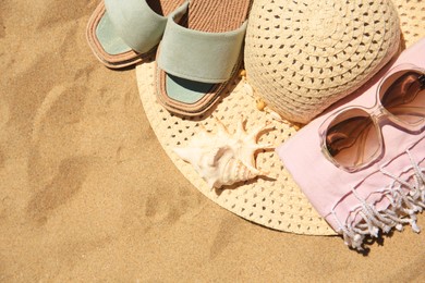 Photo of Straw hat, sunglasses, towel and slippers on sand, above view. Space for text