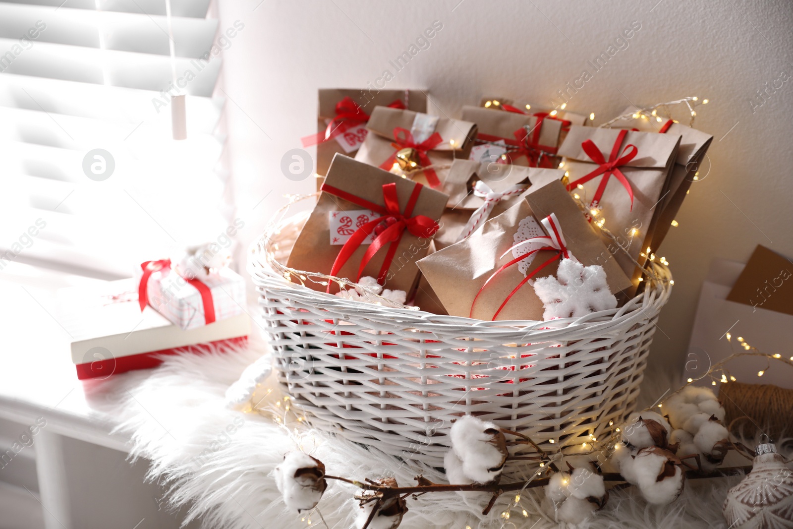 Photo of Set of gifts in basket and Christmas decor on window sill indoors. Advent calendar