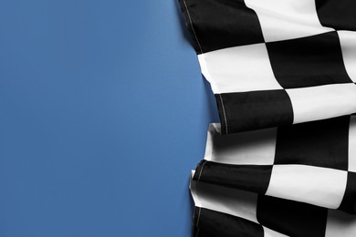 Photo of Checkered finish flag on blue background, top view. Space for text