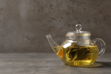 Glass teapot with oolong on table against grey background. Space for text