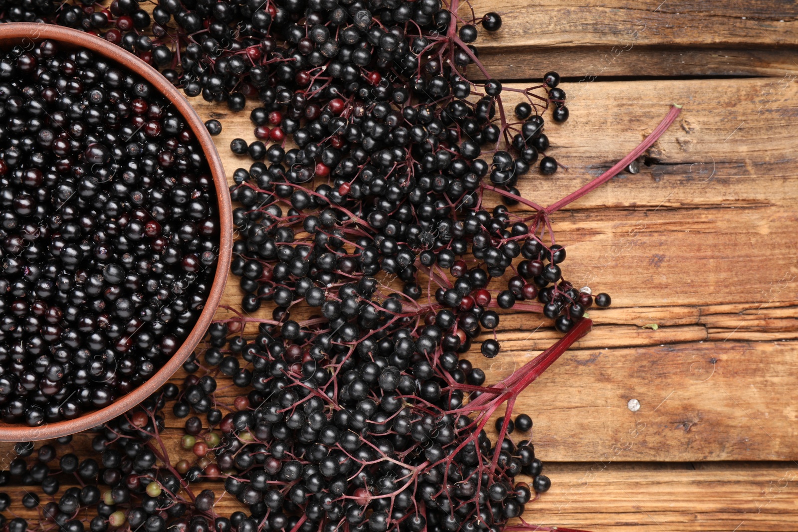 Photo of Elderberries (Sambucus) on wooden table, flat lay. Space for text