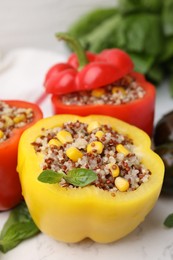 Photo of Quinoa stuffed bell peppers and basil on white table, closeup