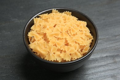 Raw farfalle pasta in bowl on grey table, closeup