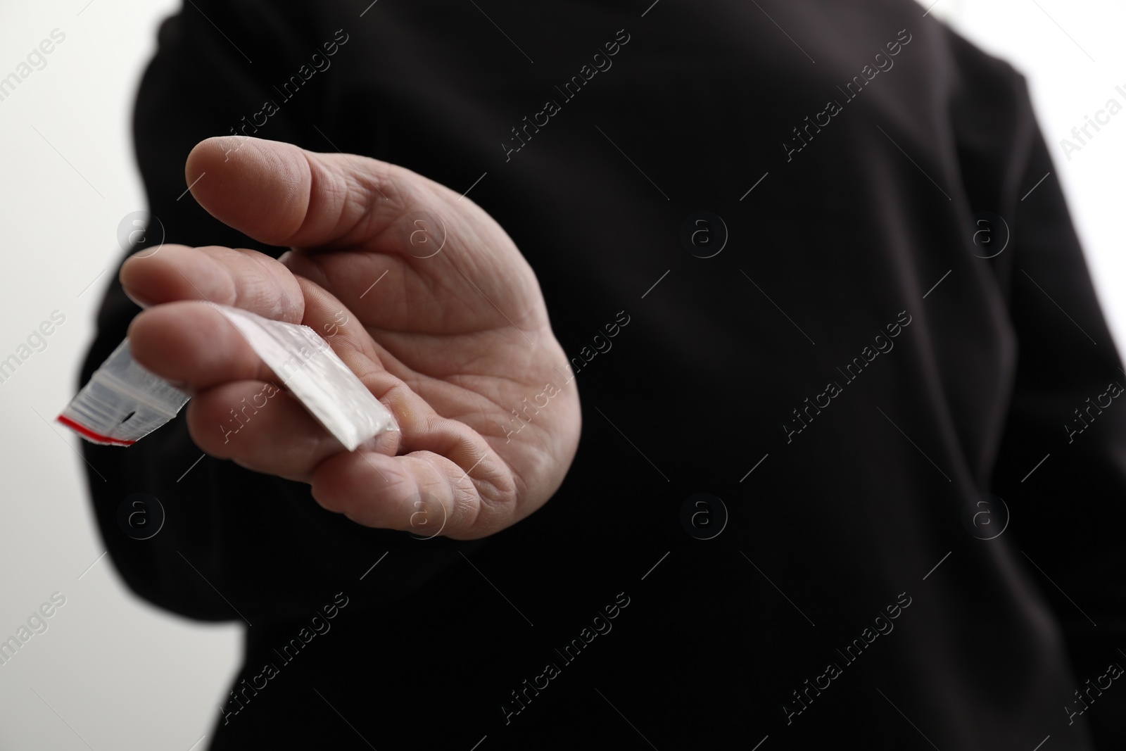 Photo of Drug addiction. Man with plastic bag of cocaine on light background, closeup