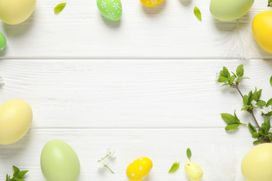 Frame made with Easter eggs on white wooden background, flat lay. Space for text